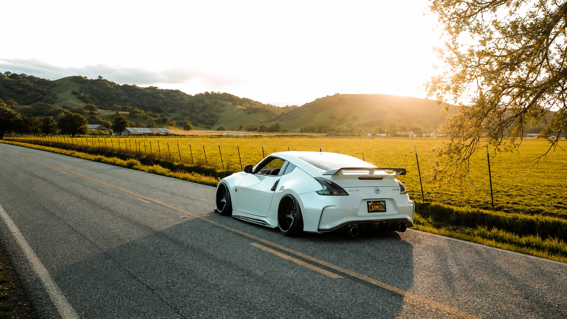 White widebody Nissan 370Z built by 38Carmodz parked on a country road at sunset